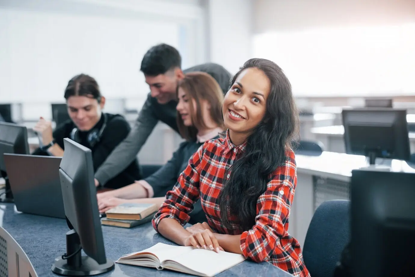 In positiver Stimmung arbeitet eine Gruppe junger Menschen in legerer Kleidung im modernen Büro.